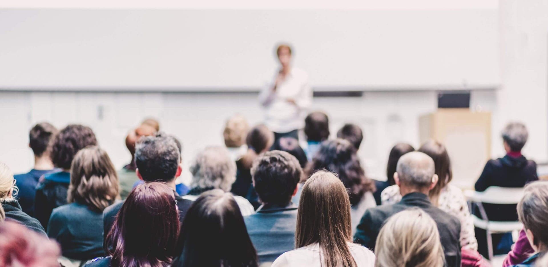 Saal mit Publikum und Rednerin während einer Tagung