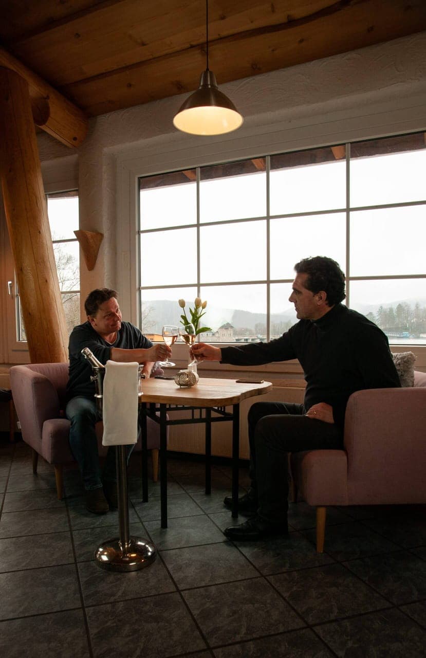 Two guests toasting with rose wine at the Panorama Bar with a view over Lake Edersee